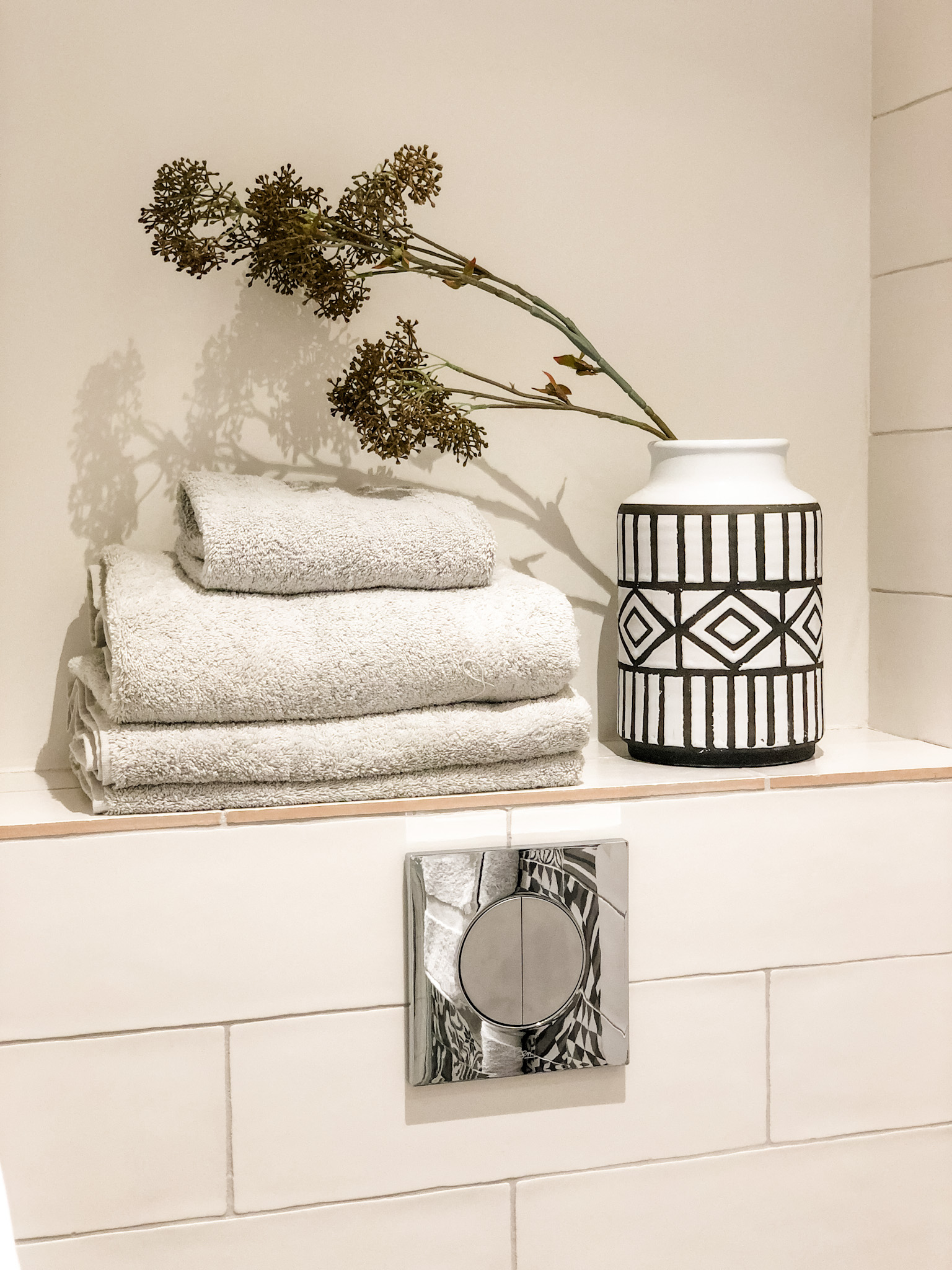 white subway tile bathroom with shelf above toilet