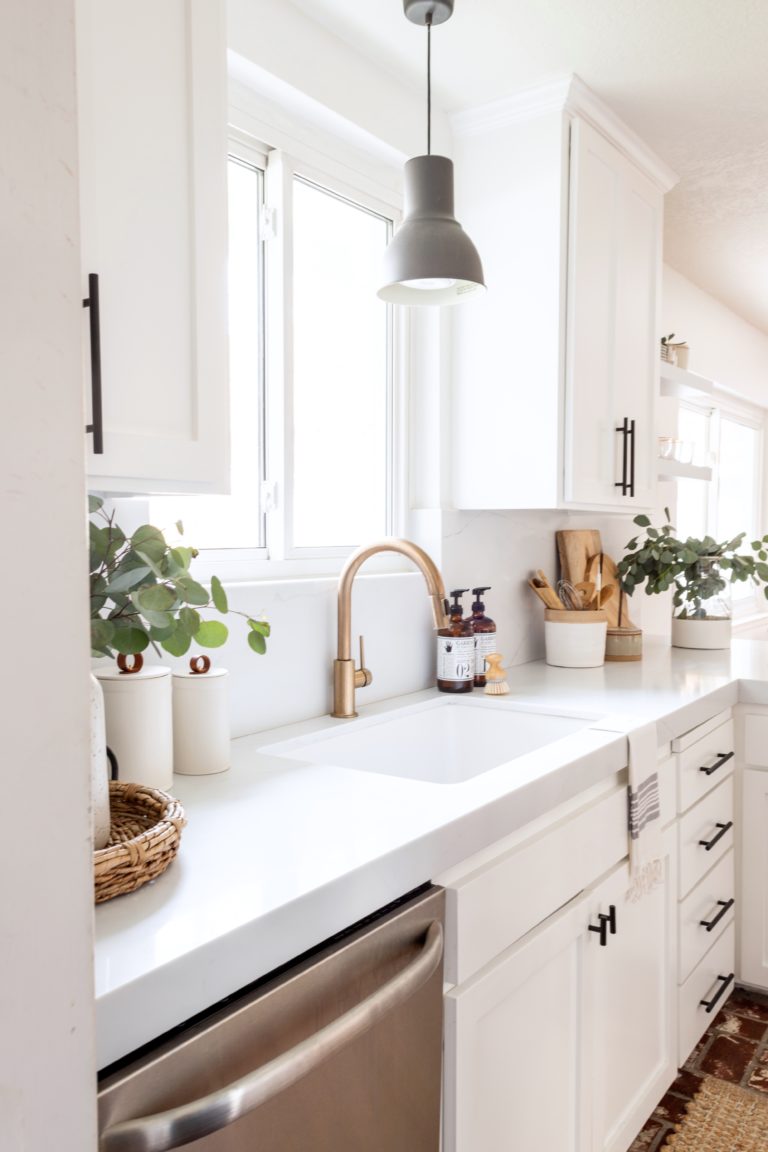 white marble counter with white cabinets and gold faucet