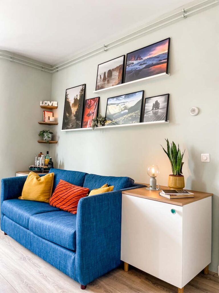 Blue couch with side tables and picture shelf