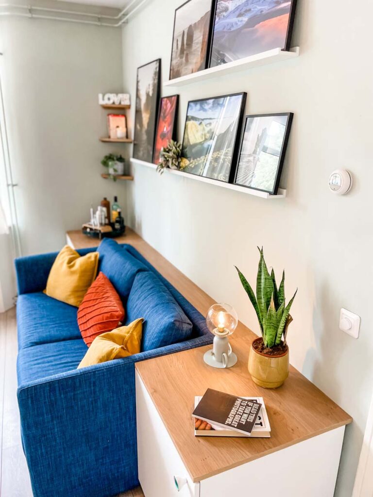 Blue couch with side tables and picture shelf