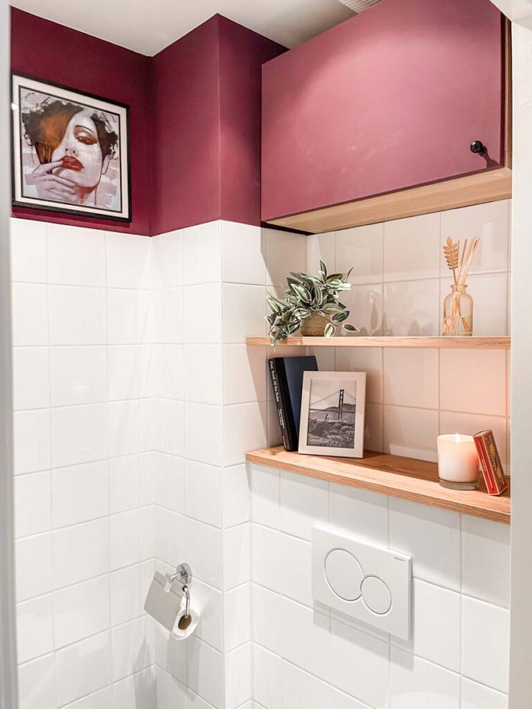 Burgundy bathroom with wooden shelves above toilet