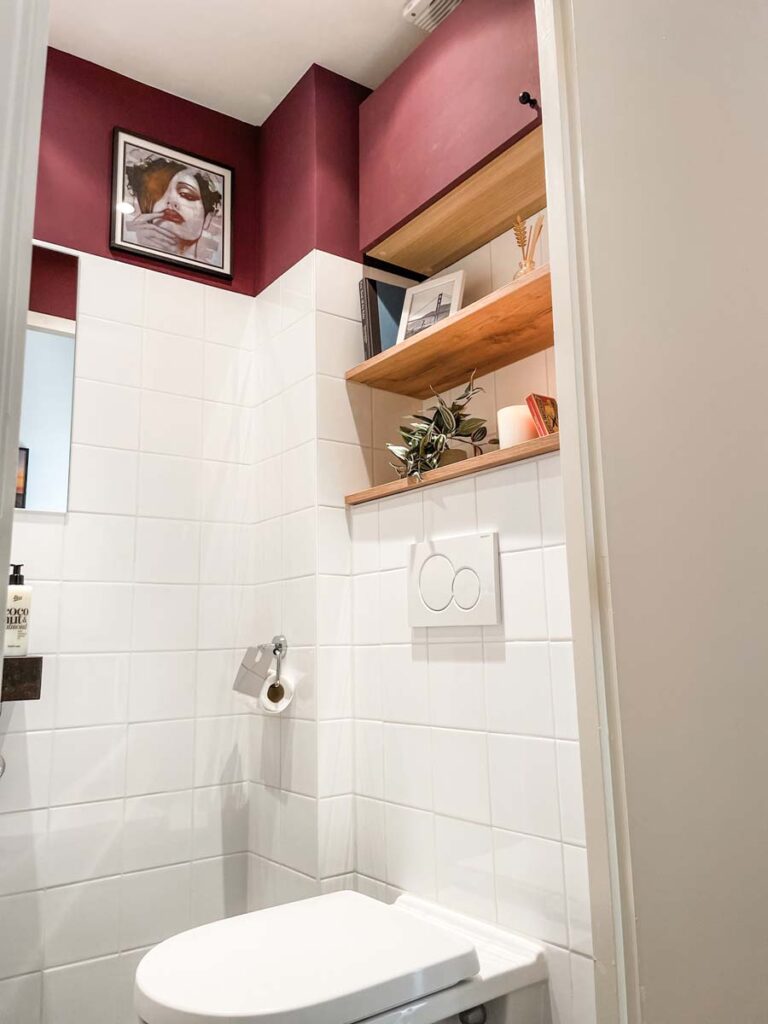 Burgundy bathroom with wooden shelves above toilet