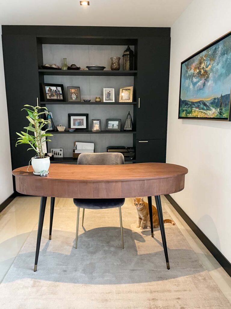 floor to ceiling black built in bookshelf in home office with wooden desk