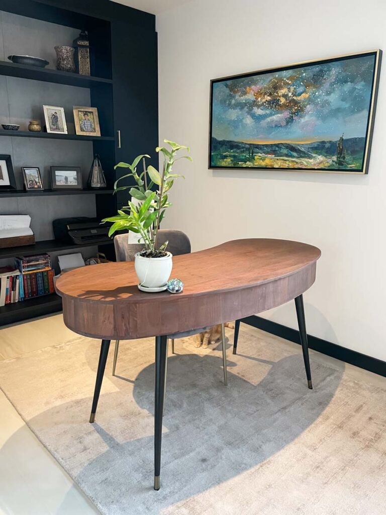 floor to ceiling black built in bookshelf in home office with wooden desk