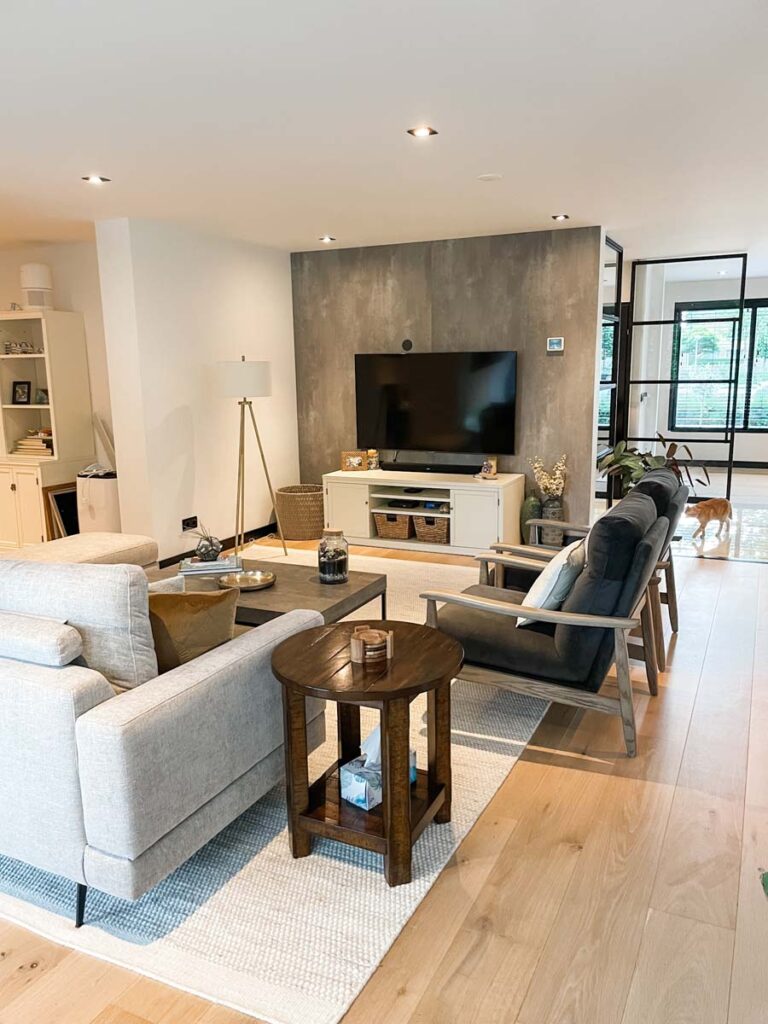 neutral living room with tree seater sofa and two arm chairs facing TV